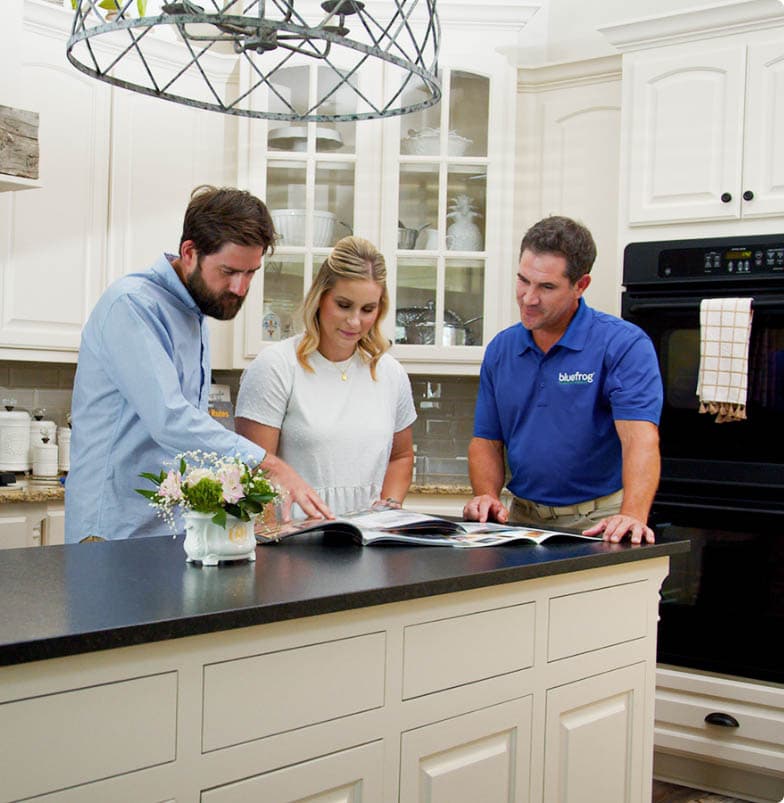 A bluefrog Plumbing + Drain plumber talking with homeowners in their kitchen