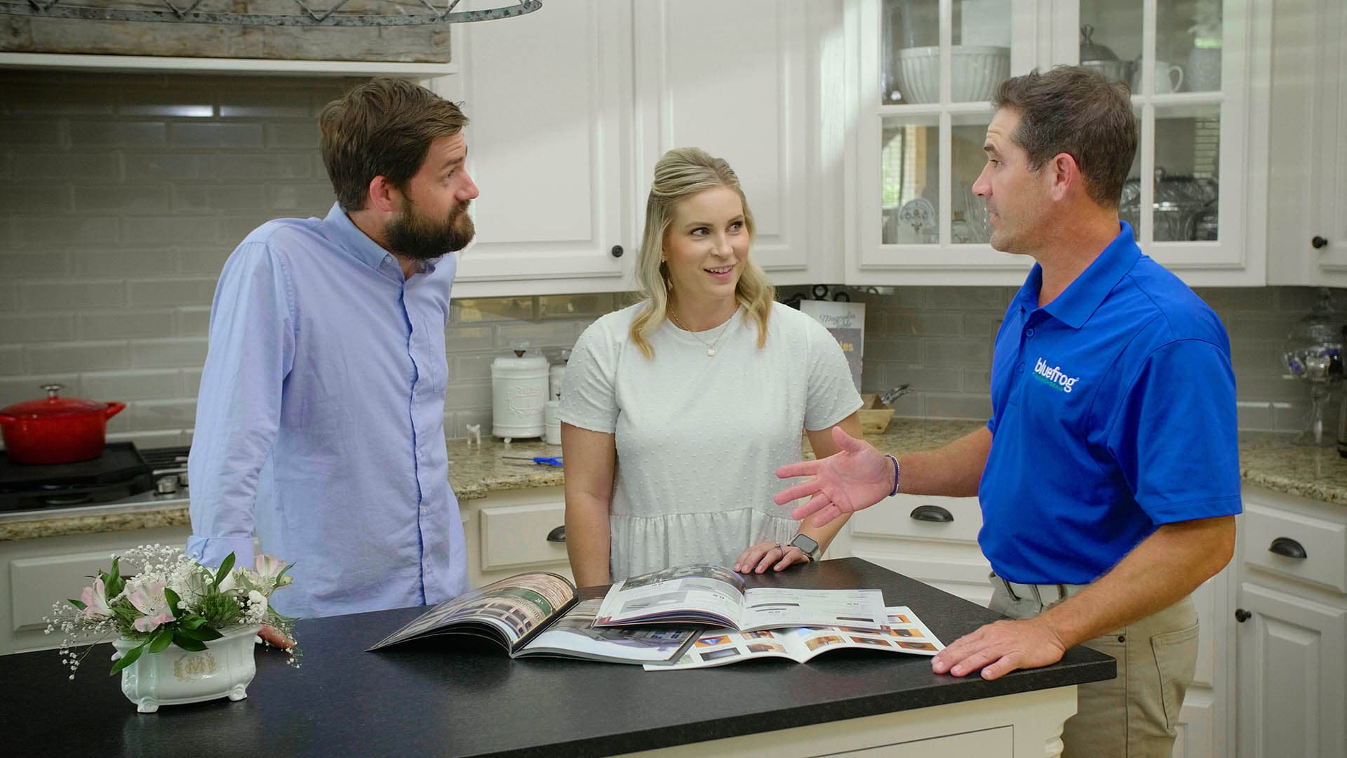 A bluefrog Plumbing + Drain plumber talking with homeowners in their kitchen