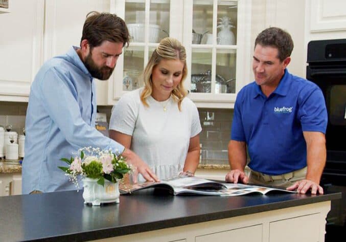 A bluefrog Plumbing + Drain plumber talking with homeowners in their kitchen